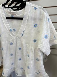 Neckline detail of the white top with blue and yellow daisies embroidery 