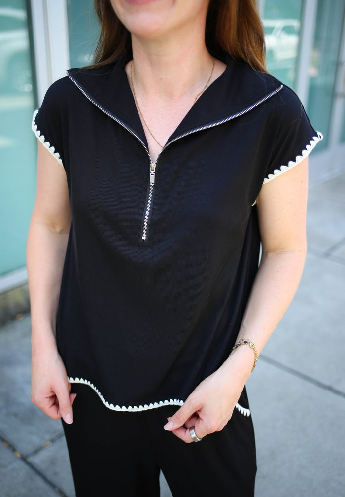 Black top with quarter zip neckline and white stitch hem details